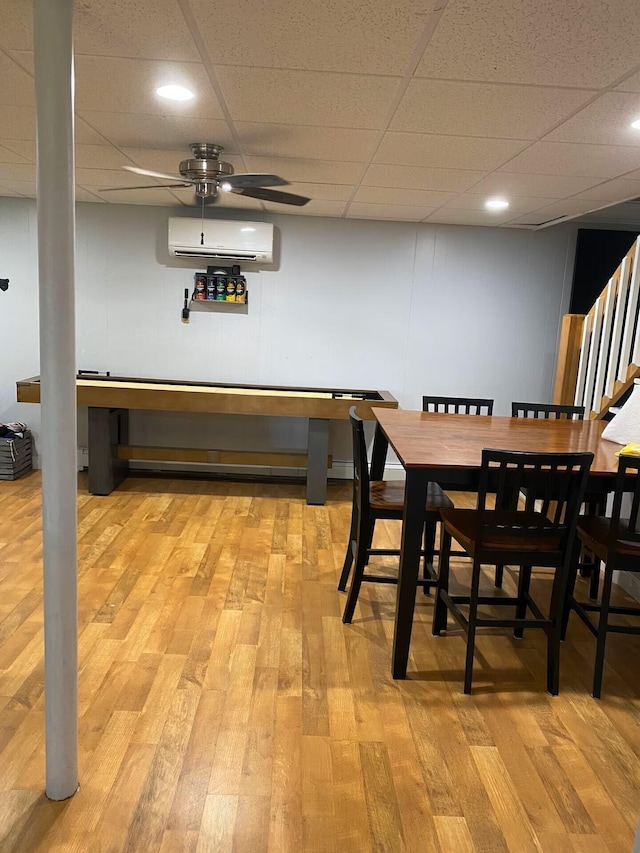 dining space featuring ceiling fan, stairway, a paneled ceiling, light wood-style floors, and a wall mounted AC