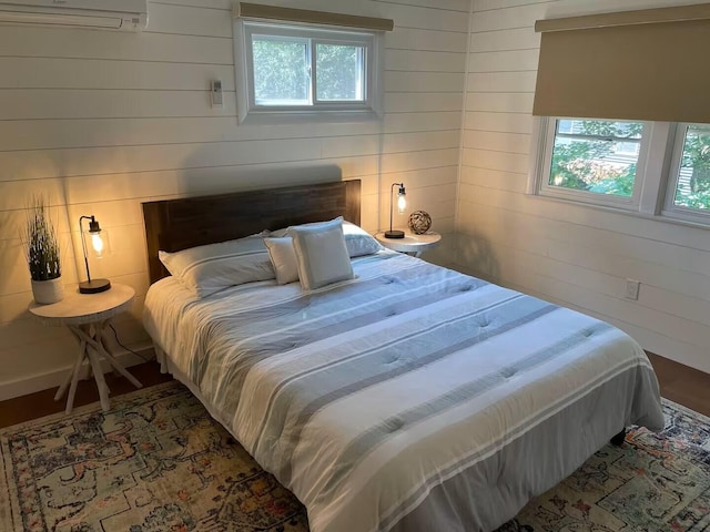 bedroom with multiple windows, a wall mounted air conditioner, and wooden walls