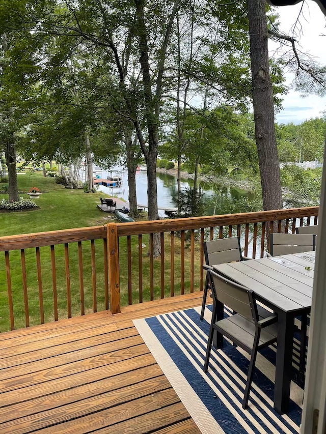 wooden deck featuring a water view, outdoor dining area, and a yard