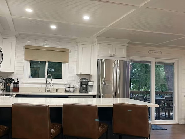 kitchen featuring a sink, white cabinetry, decorative backsplash, dark wood-style floors, and stainless steel fridge