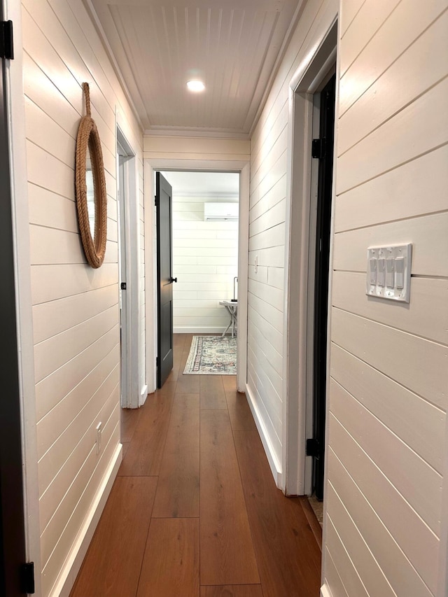 corridor with wooden walls, an AC wall unit, dark wood finished floors, and crown molding