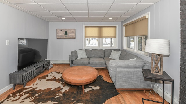 living room featuring a drop ceiling, baseboards, and wood finished floors