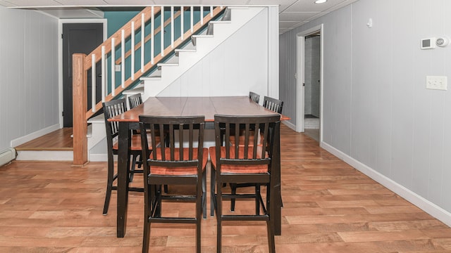 dining space with light wood-style floors, baseboards, and stairway