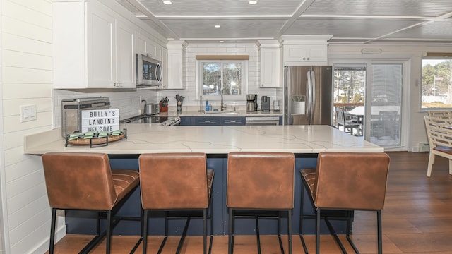 kitchen featuring stainless steel appliances, white cabinets, a peninsula, and light stone counters