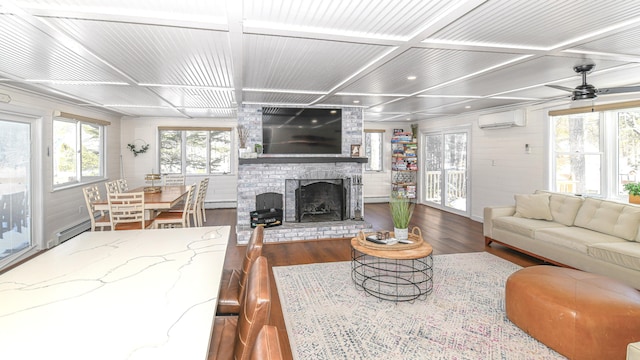 living room featuring a baseboard heating unit, coffered ceiling, wood finished floors, a wall mounted AC, and a brick fireplace