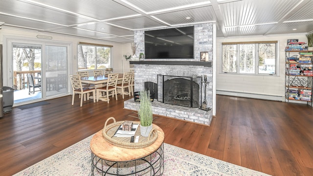 living area with coffered ceiling, baseboard heating, a brick fireplace, and wood finished floors