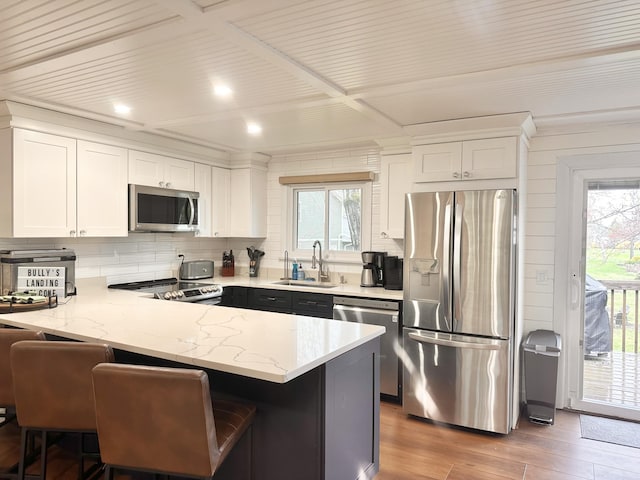 7 Birch Dr, Raymond, ME 04071 - kitchen with a sink, stainless steel appliances, backsplash, a peninsula, and white cabinetry