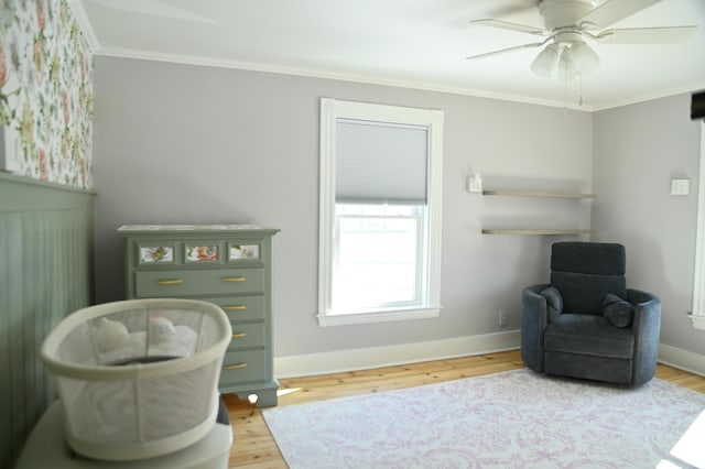 sitting room featuring a ceiling fan, baseboards, ornamental molding, and wood finished floors