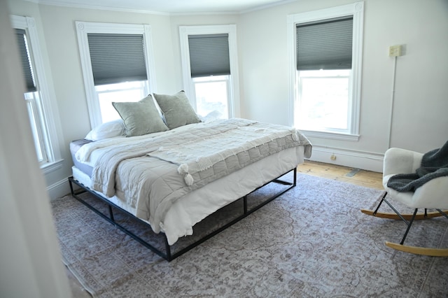 bedroom featuring ornamental molding, wood finished floors, and baseboards