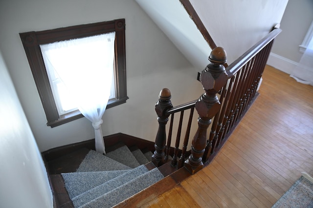 stairs with baseboards, vaulted ceiling, and wood finished floors