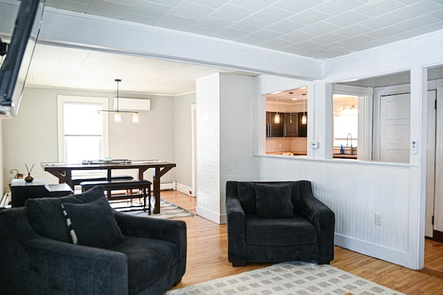 living room featuring baseboards, an AC wall unit, wood finished floors, and crown molding