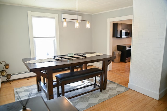 dining room featuring a baseboard heating unit, ornamental molding, and light wood-style floors