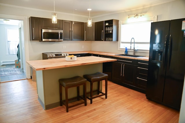 kitchen with a baseboard radiator, appliances with stainless steel finishes, light wood-style floors, wooden counters, and a sink