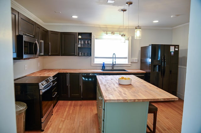 kitchen with a breakfast bar, a sink, light wood-style floors, wooden counters, and black appliances