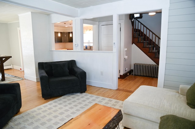 living area with stairway, radiator heating unit, a baseboard radiator, and wood finished floors