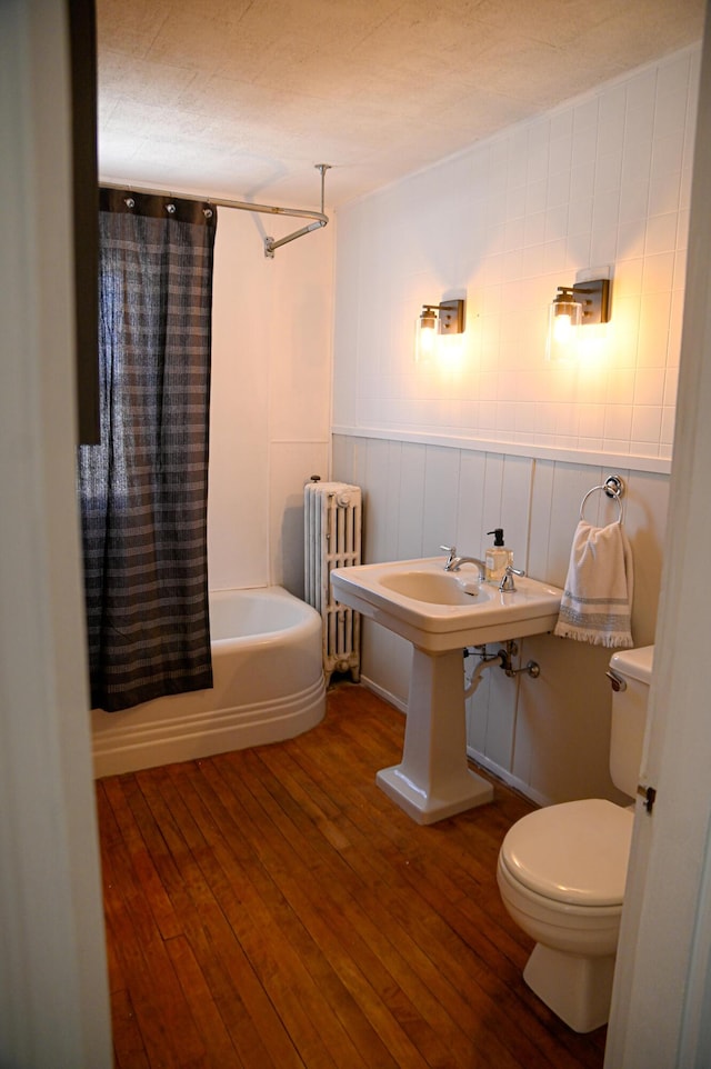 bathroom with shower / bathtub combination with curtain, hardwood / wood-style floors, toilet, and radiator