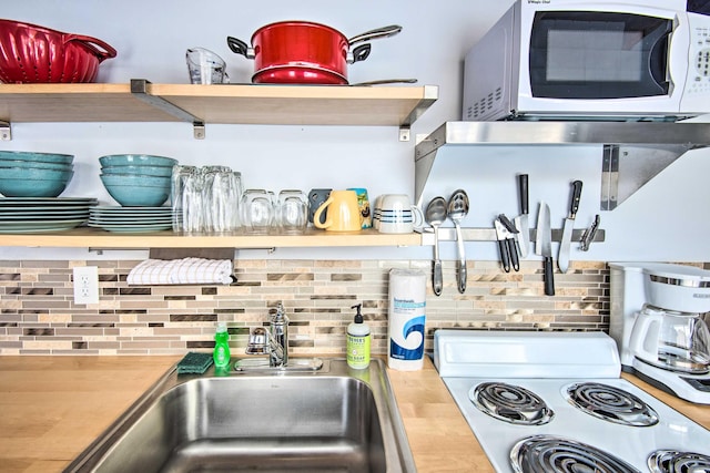 kitchen featuring open shelves, light countertops, backsplash, a sink, and white appliances