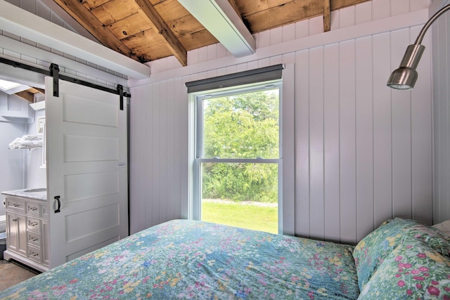 bedroom featuring wood ceiling, vaulted ceiling with beams, a barn door, and wooden walls