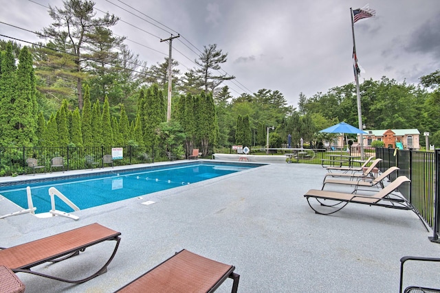 pool with a patio area and fence