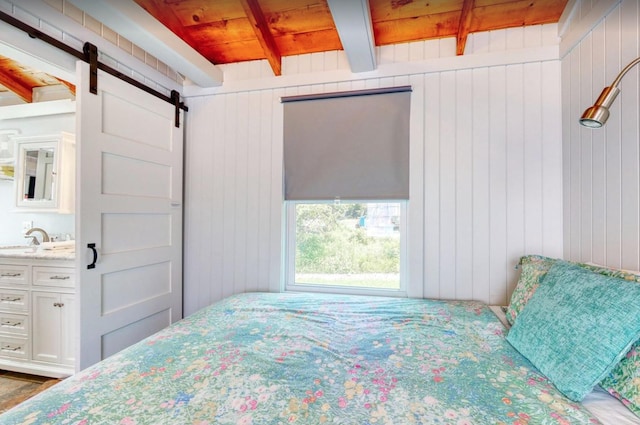 bedroom with a barn door, wood walls, a sink, wooden ceiling, and beamed ceiling