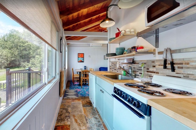 kitchen with tasteful backsplash, light countertops, stone finish floor, a sink, and white appliances