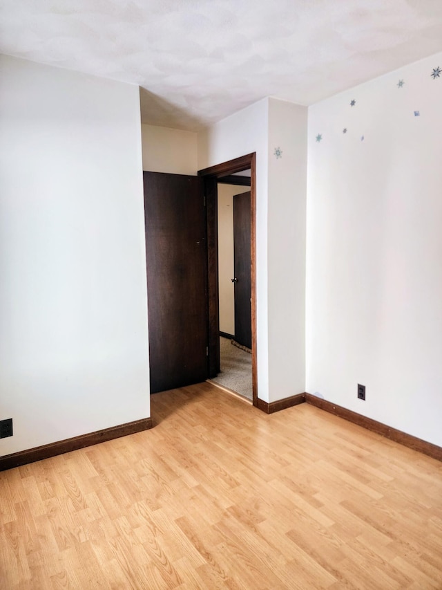 unfurnished room with baseboards and light wood-style floors