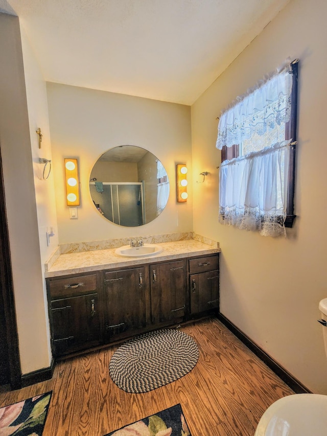 full bath with vanity, wood finished floors, baseboards, an enclosed shower, and toilet