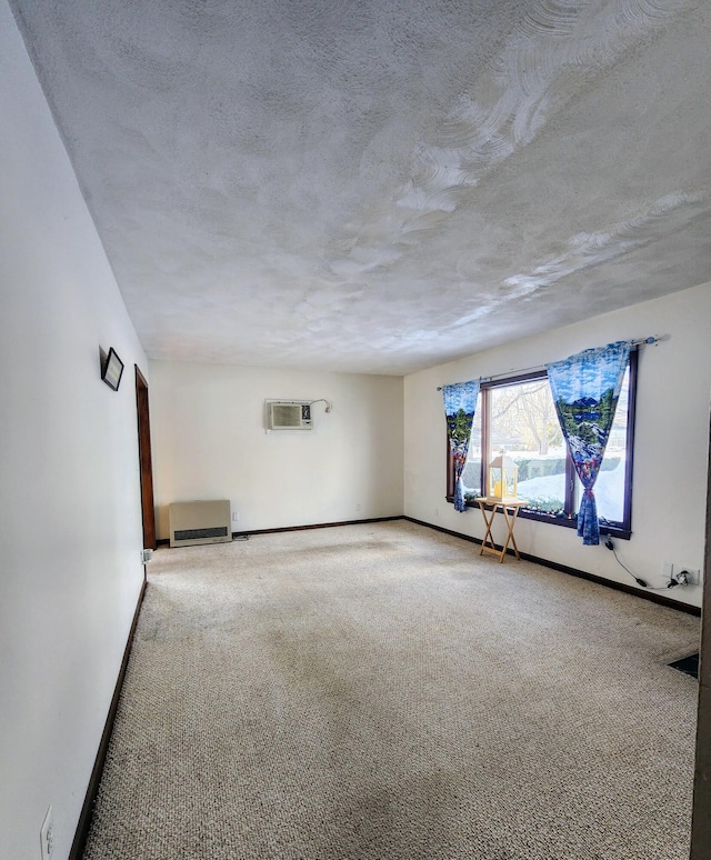 carpeted empty room featuring a textured ceiling, a wall mounted AC, and baseboards