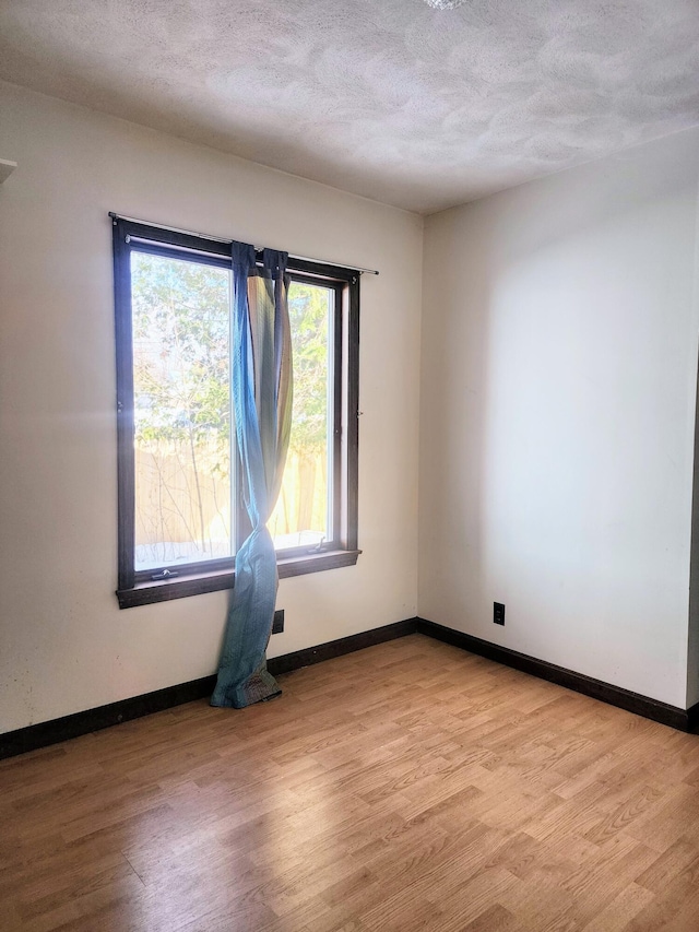 unfurnished room featuring light wood-style floors and a textured ceiling