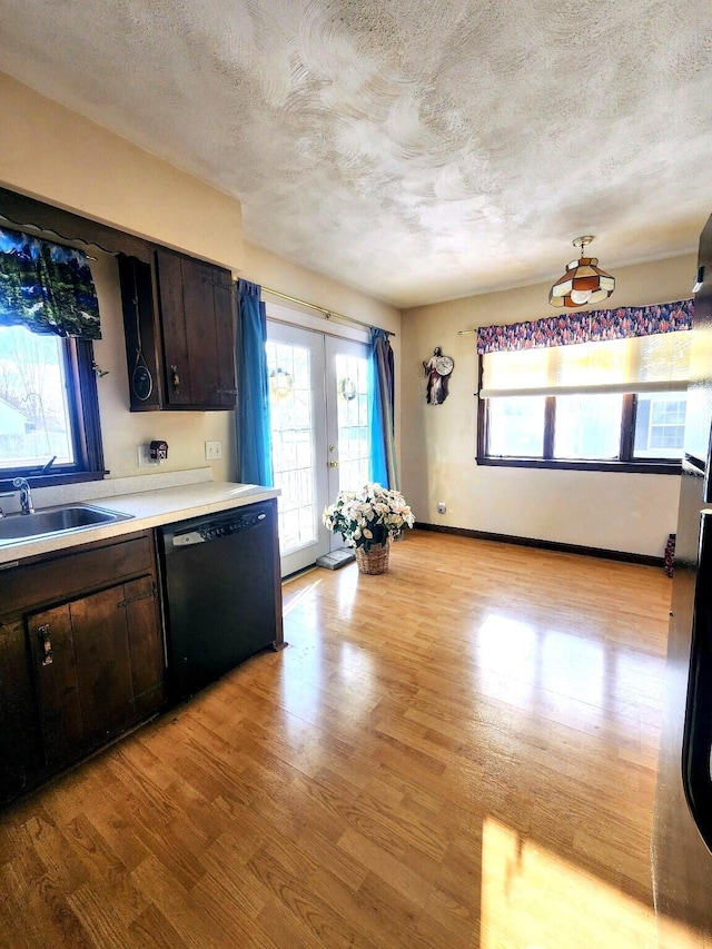 kitchen with a textured ceiling, light wood-type flooring, black dishwasher, and a sink