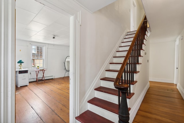 staircase featuring hardwood / wood-style flooring, baseboards, and a baseboard radiator