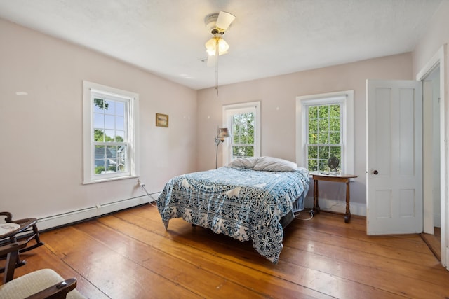 bedroom with wood-type flooring, ceiling fan, and a baseboard radiator