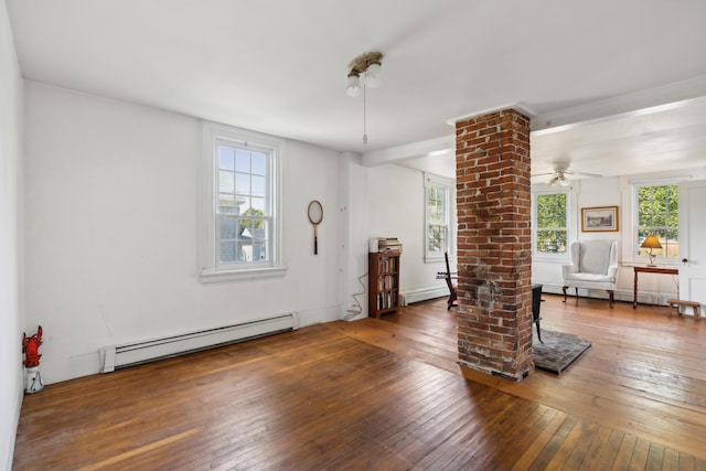 empty room with ceiling fan, decorative columns, baseboard heating, and hardwood / wood-style floors