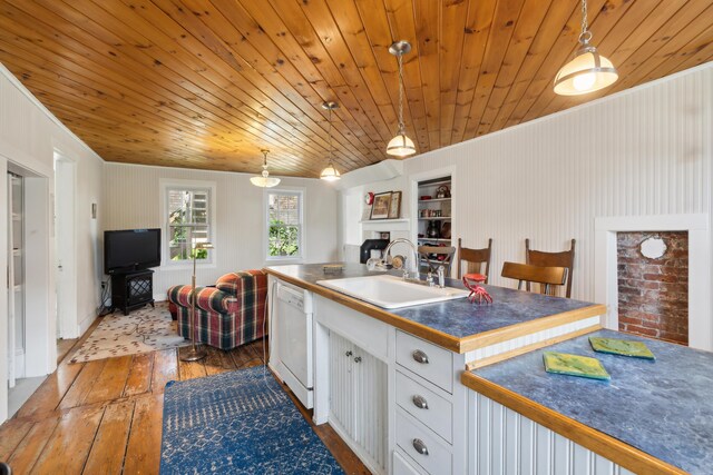 kitchen with dark countertops, a sink, open floor plan, and white dishwasher