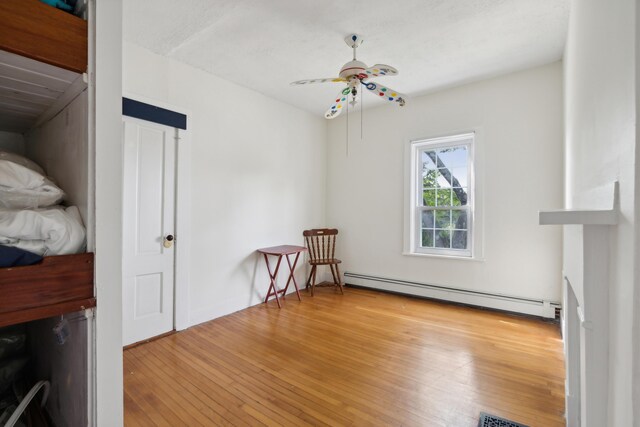 interior space with a ceiling fan, light wood finished floors, and a baseboard radiator