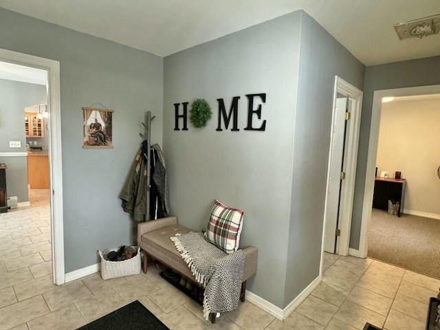 mudroom with light tile patterned flooring, light carpet, and baseboards