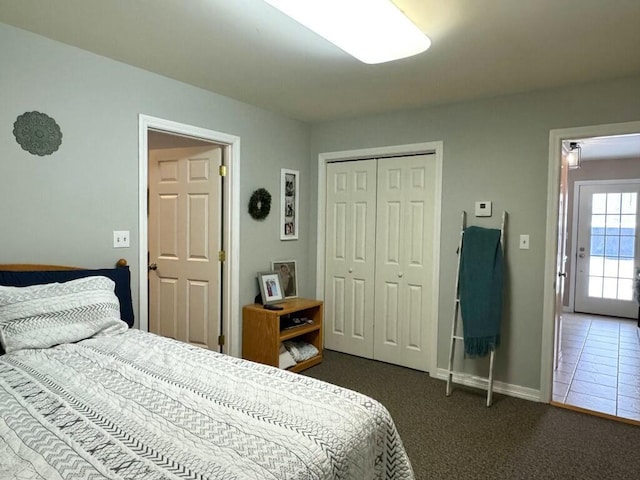 bedroom with baseboards, dark carpet, and a closet