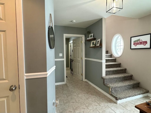 corridor featuring light tile patterned floors, stairway, and baseboards