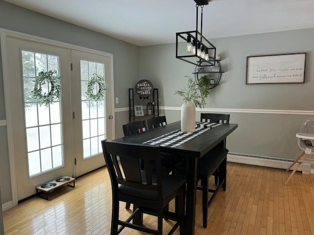 dining space featuring a healthy amount of sunlight, light wood finished floors, and a baseboard radiator