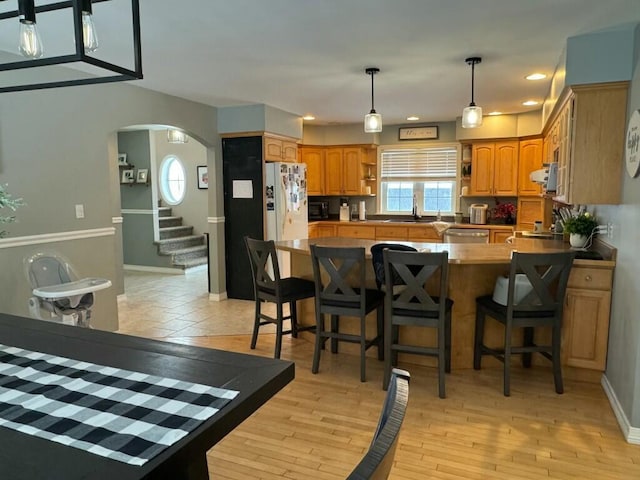 kitchen featuring arched walkways, freestanding refrigerator, a peninsula, a sink, and stainless steel dishwasher