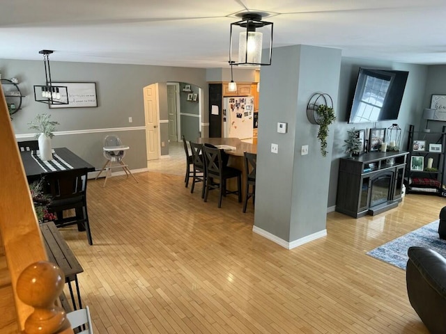 living area featuring arched walkways, baseboards, and light wood-style floors