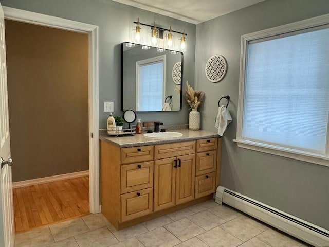 bathroom with a baseboard heating unit, tile patterned flooring, vanity, and baseboards