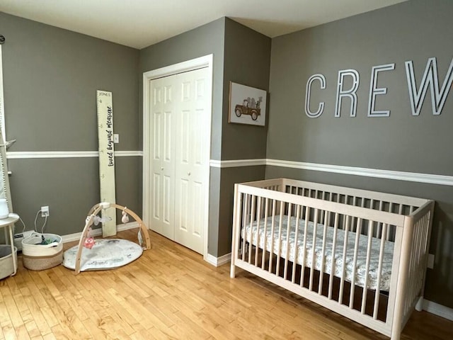 bedroom featuring a nursery area, wood finished floors, and baseboards