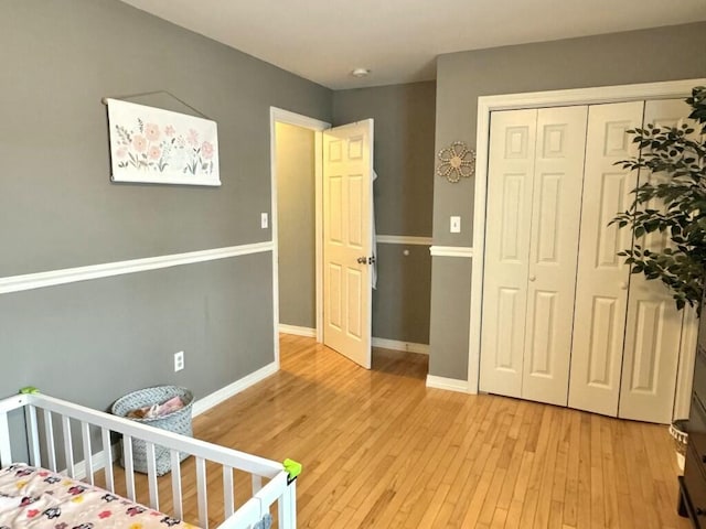 bedroom featuring light wood finished floors, baseboards, and a closet