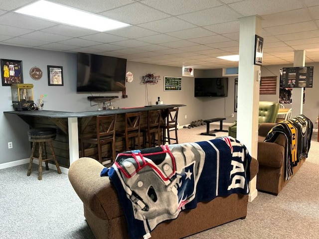 living room with baseboards, carpet floors, a drop ceiling, and wet bar