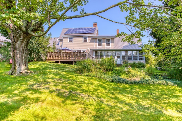 back of house with metal roof, a yard, a deck, and a chimney