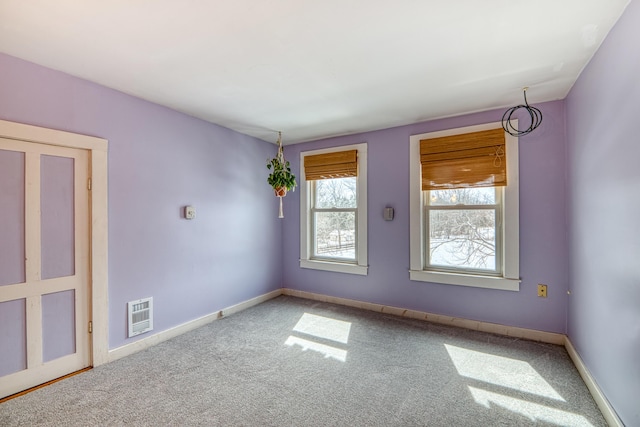 spare room featuring carpet flooring, visible vents, and baseboards