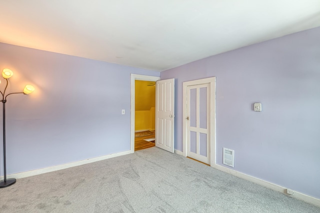 carpeted empty room with visible vents and baseboards