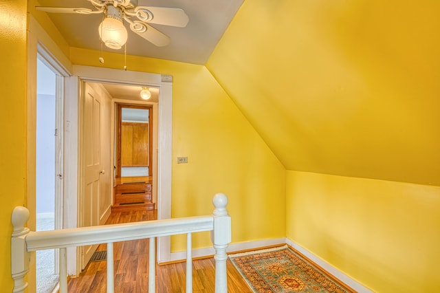 hall featuring vaulted ceiling, wood finished floors, an upstairs landing, and baseboards