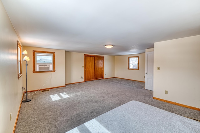 carpeted spare room featuring cooling unit, visible vents, and baseboards